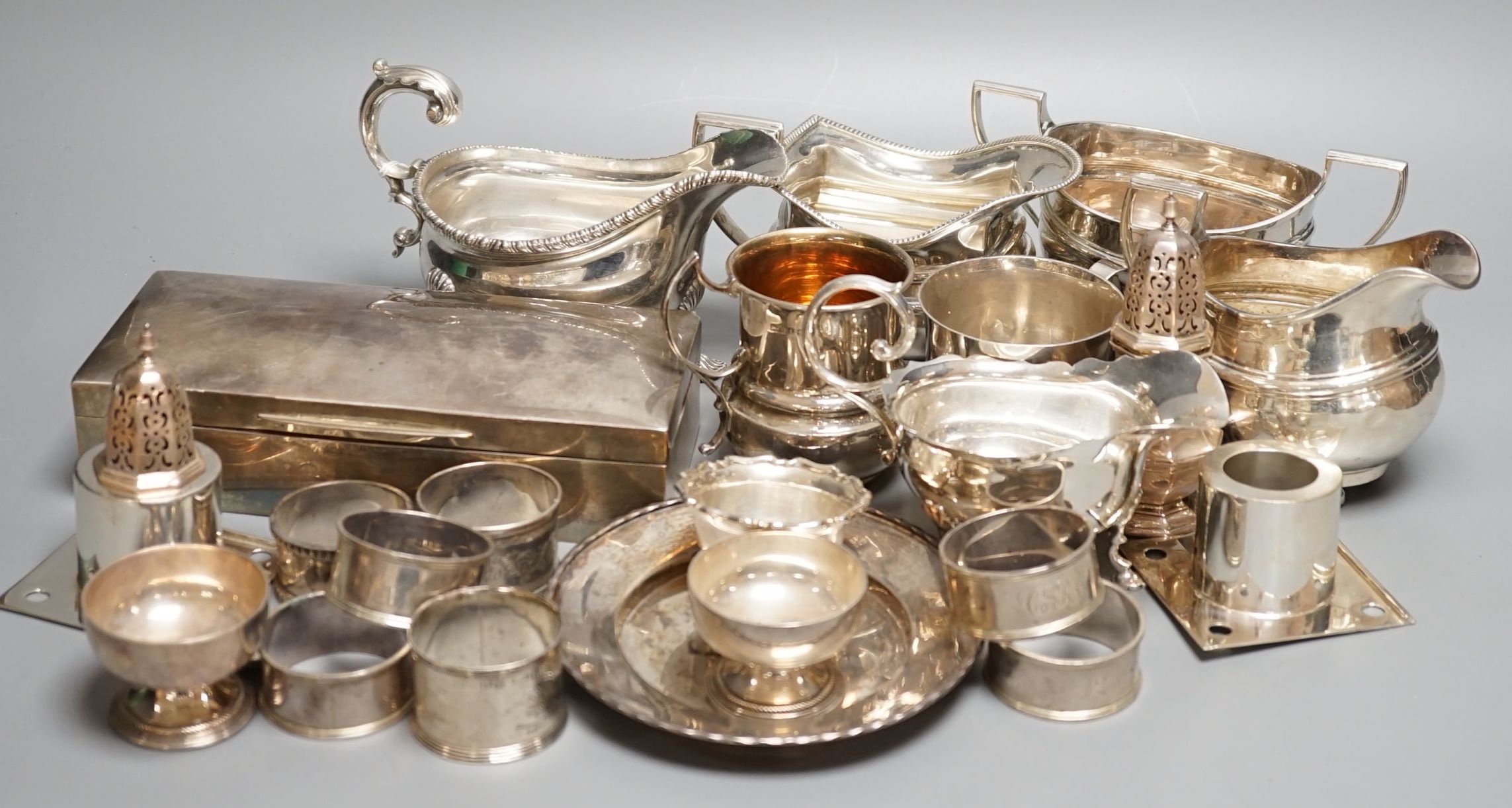 A quantity of assorted mainly 20th century sundry silver including three cream jugs, two silver sauceboats, two small mugs, pair of pepperettes, cigarette box, two match sleeves, pair of salts, seven napkin rings, two sc
